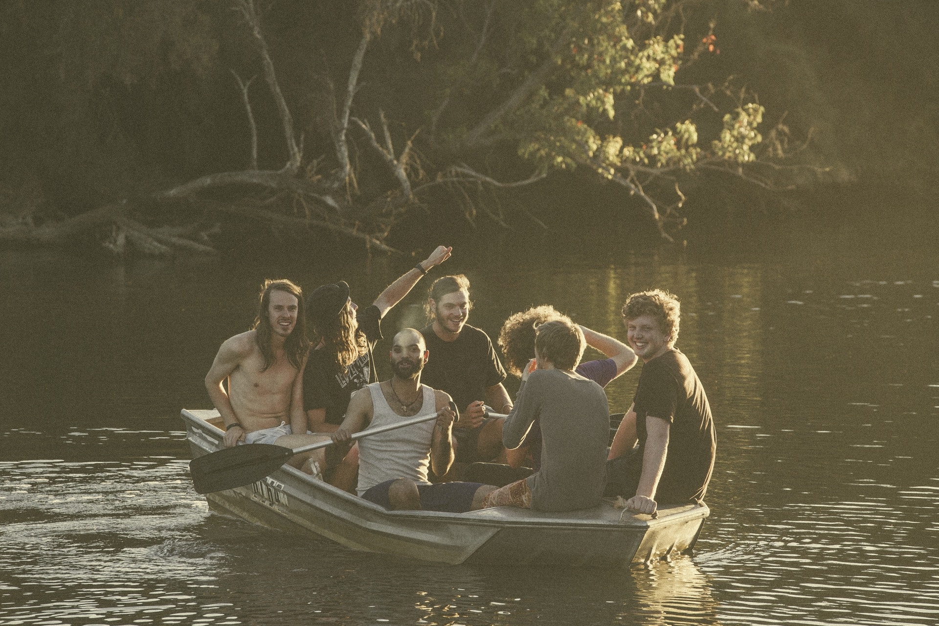 The members of Koi Child sitting in a dinghy on a river and laughing.